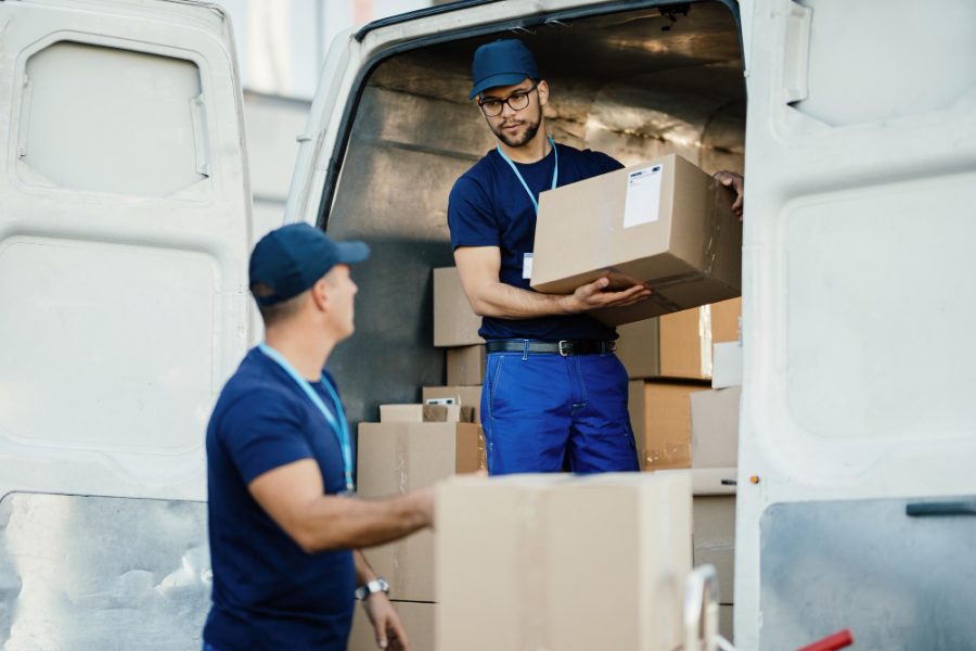 young-worker-loading-cardboard-boxes-delivery-van-communicating-with-his-colleague